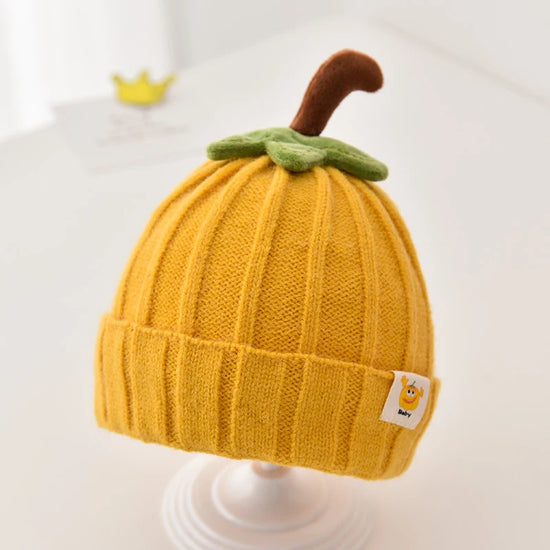 baby wearing a knitted pumpkin hat with green leaf and stem, cozy fall outfit
