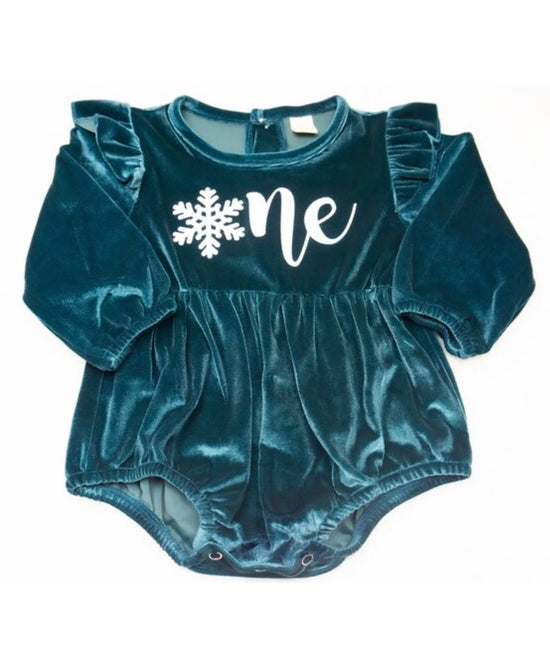 Baby girl in purple Onederland snowflake romper for 1st birthday cake smash photoshoot.