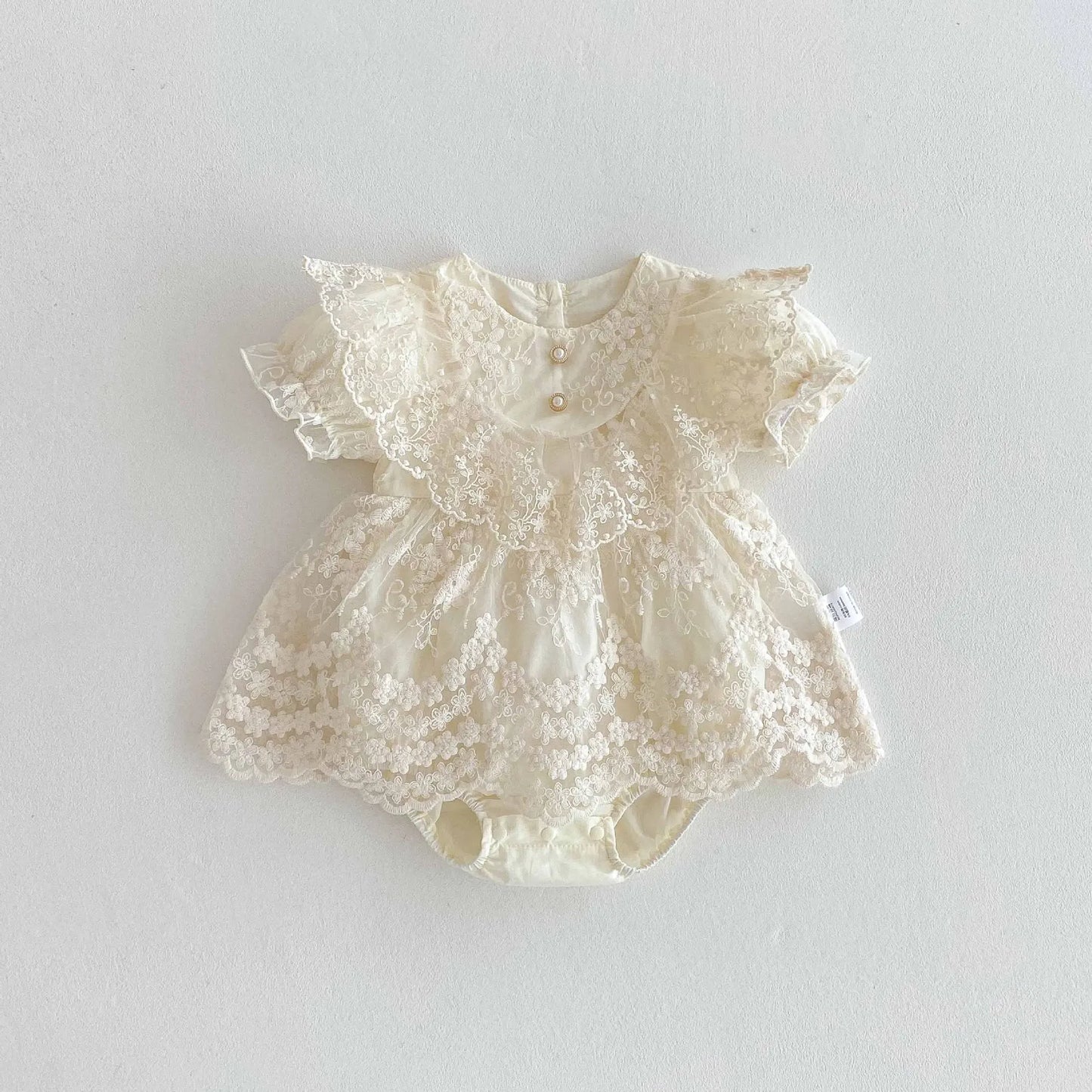 Cream-colored lace baby romper on a light gray background