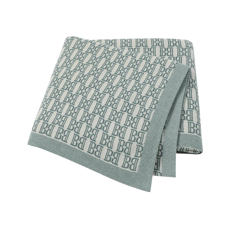 Green towel with a pattern of the letter 'B' on a white background