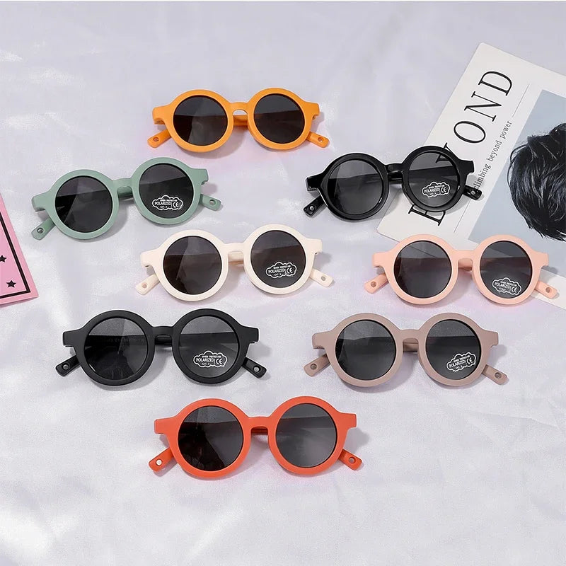 Collection of colorful children's sunglasses on a light gray background