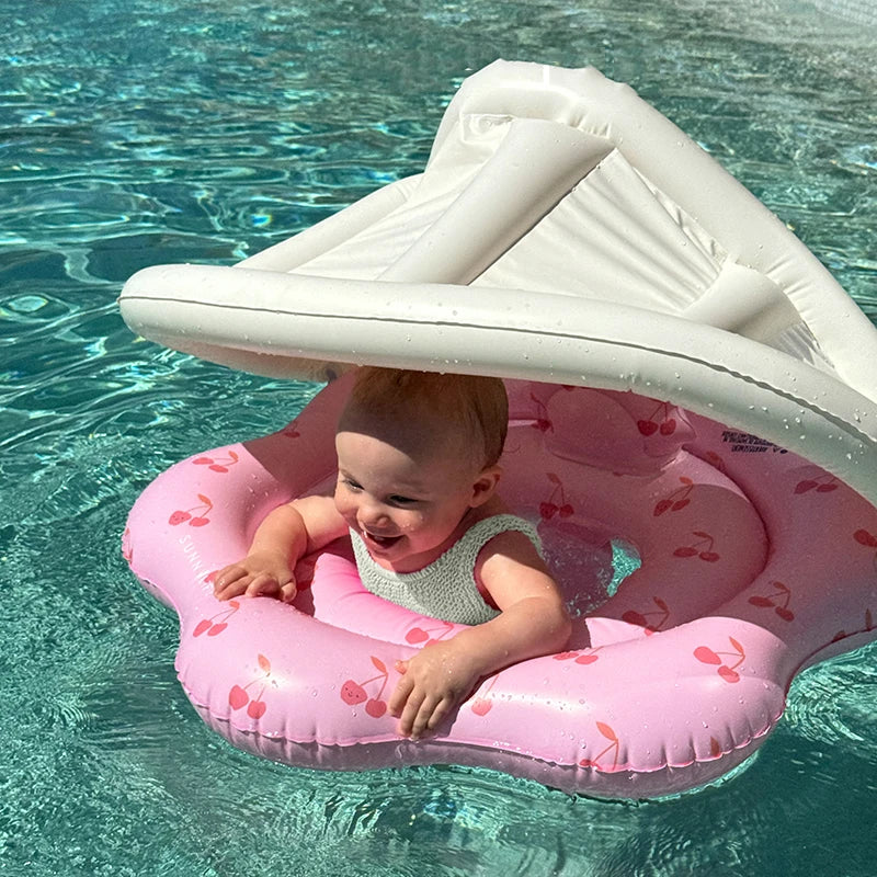 Child on a pink inflatable pool seat with a white canopy in clear blue water