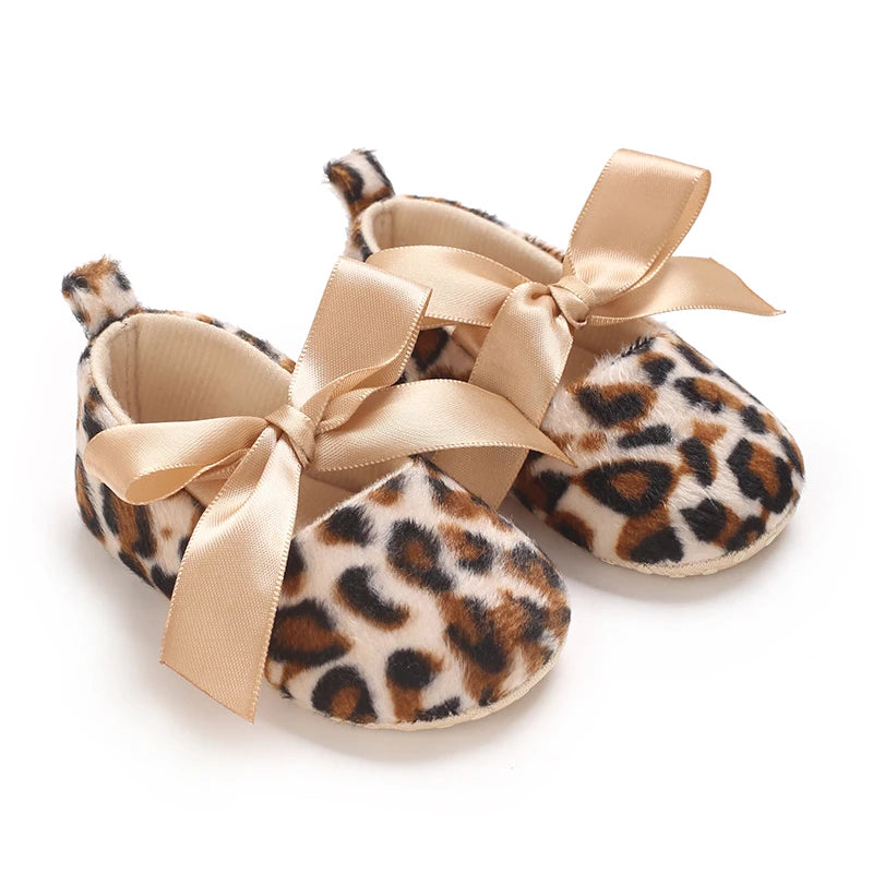 Leopard print baby shoes with ribbons on a white background