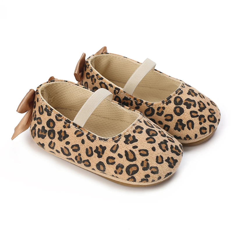 Pair of leopard print baby shoes with bows on a white background