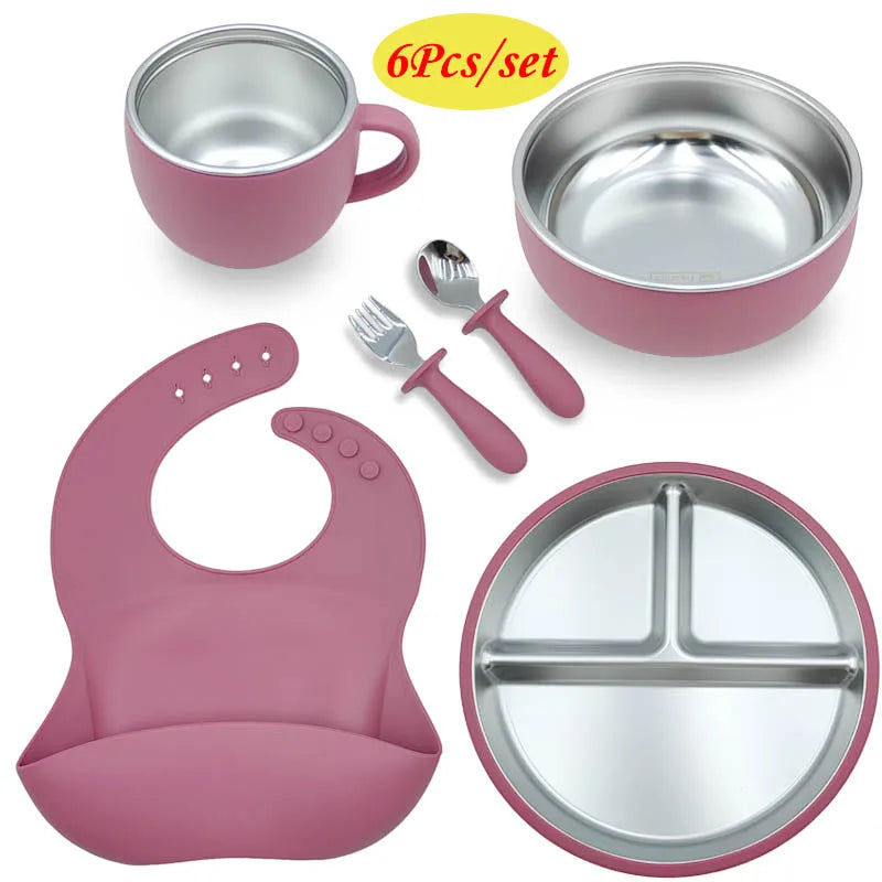 Pink children's dining set with bowls, cup, fork, spoon, and bib on a white background.