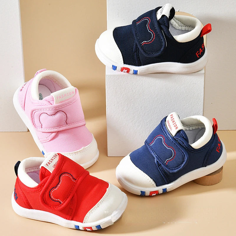 Four children's sneakers in pink, blue, and red on a beige background
