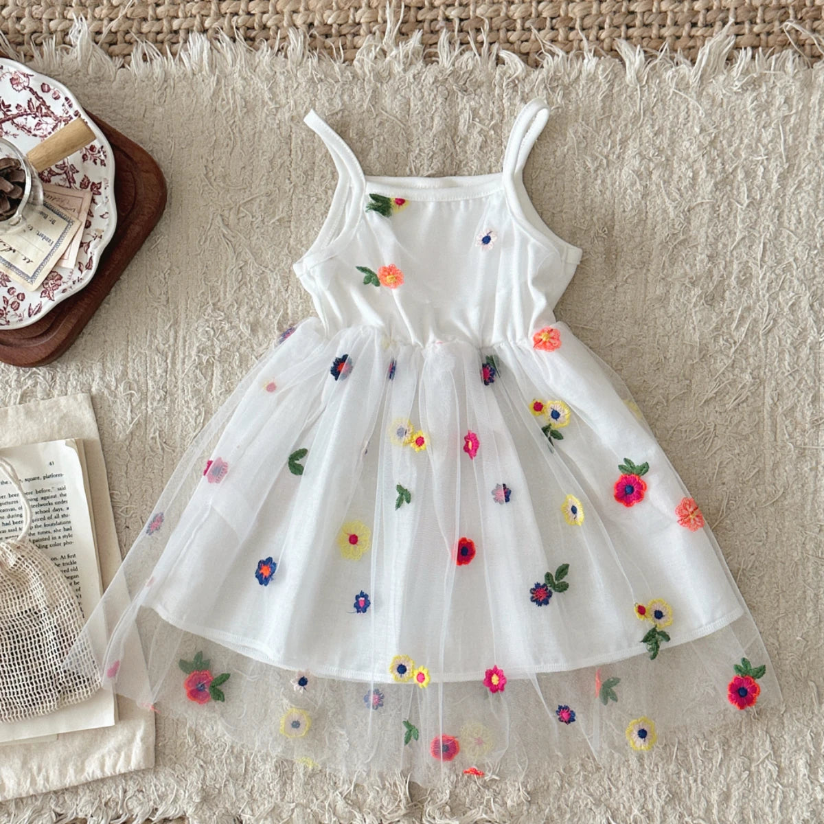 White dress with colorful floral embroidery on a textured surface