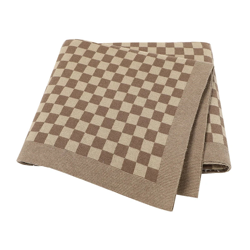 Folded checkered blanket with brown and beige pattern on a white background