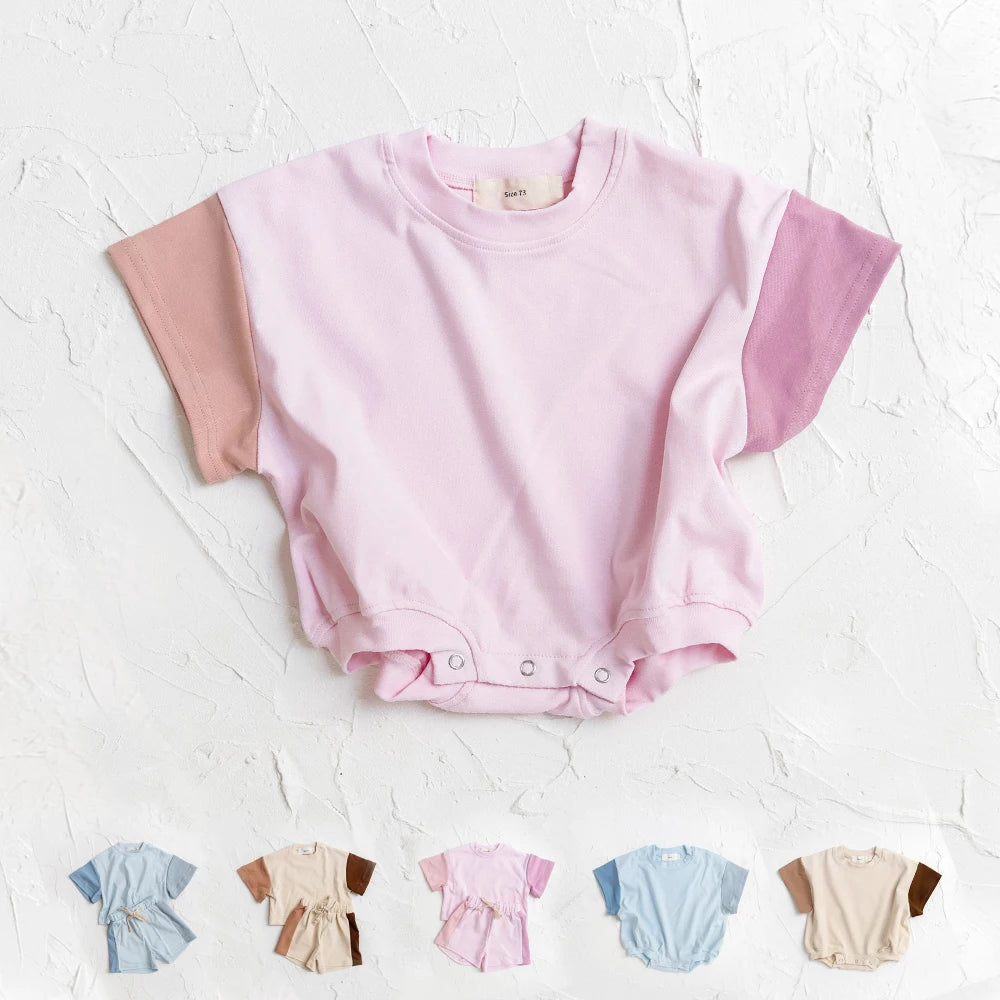 Pink baby romper with short sleeves on a textured white background