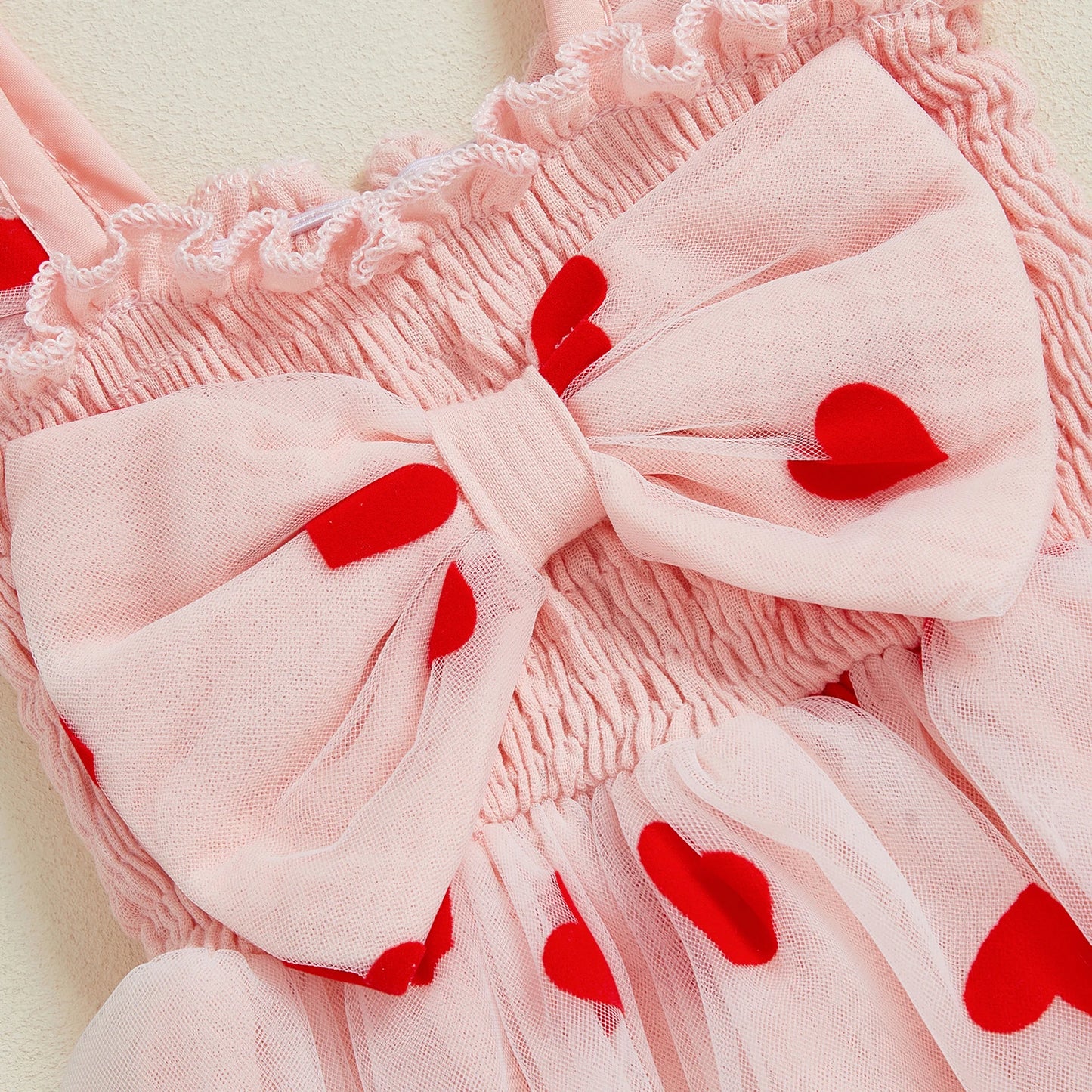 Pink outfit with a large bow and red heart details on a light background