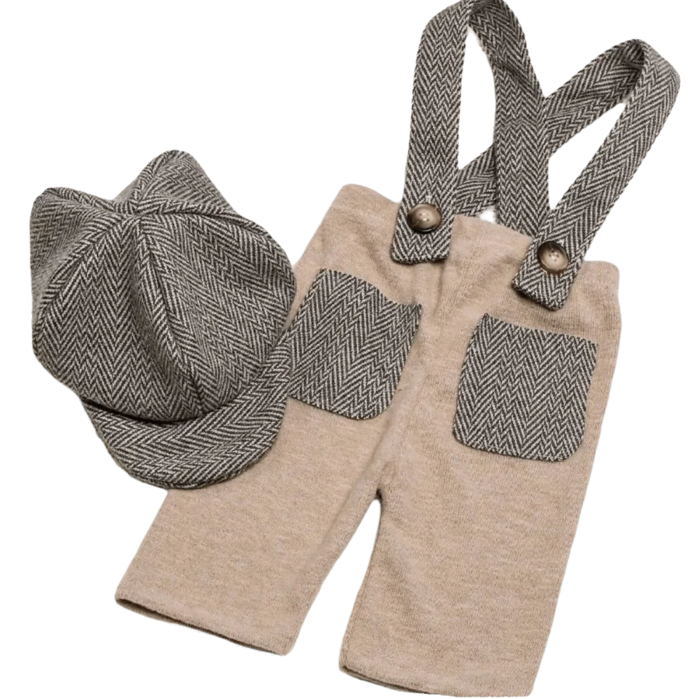 A children's two-piece outfit set featuring beige knit pants with gray herringbone patterned suspenders and matching pockets, accompanied by a matching gray herringbone flat cap, shown on a plain white background.