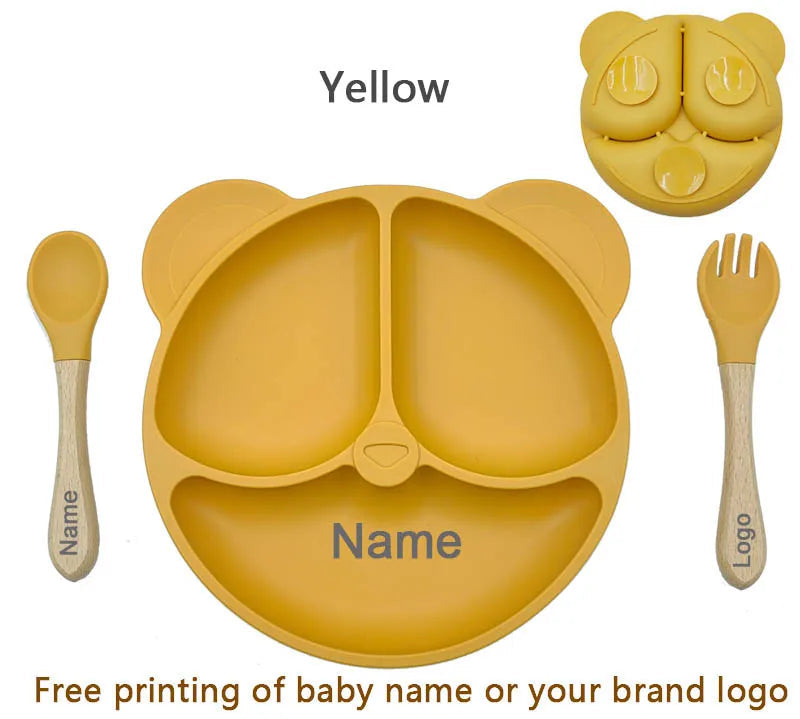 Yellow silicone baby plate with spoon, fork, and container on a white background