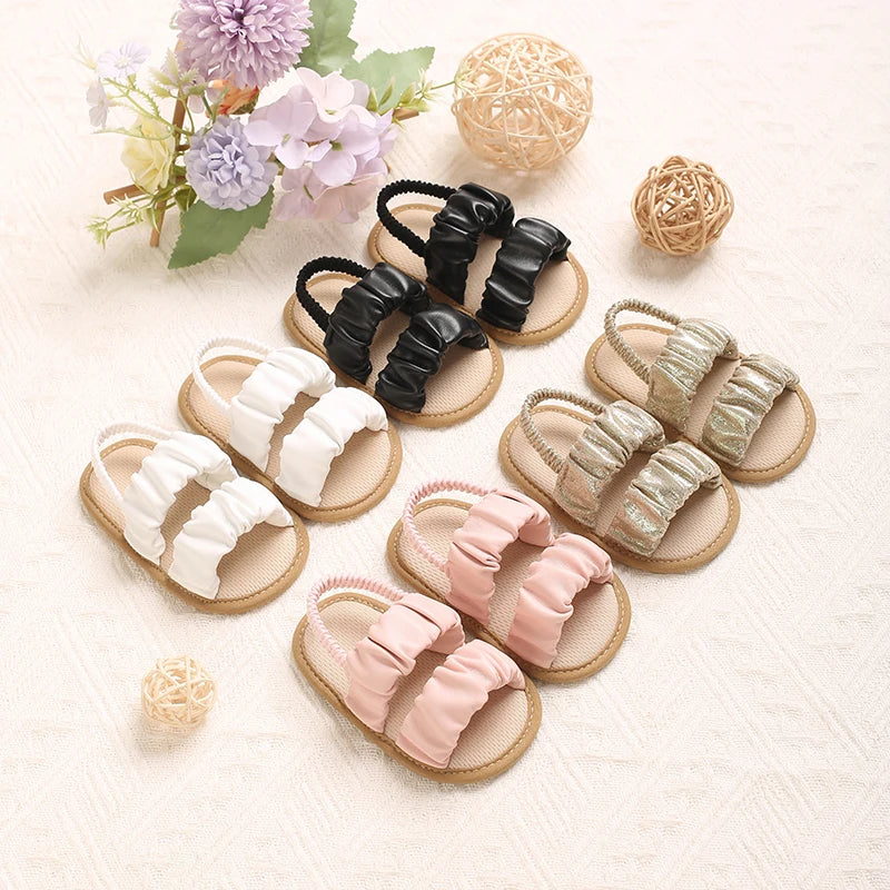Set of baby sandals in various colors on a light background with flowers.