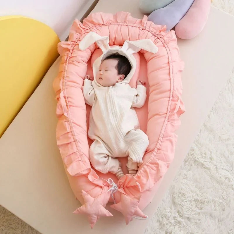 Baby sleeping in a pink crib with a soft blanket