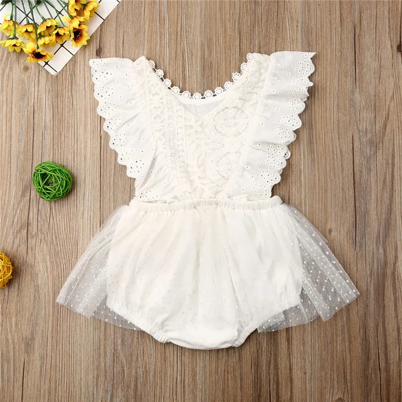 White lace romper on a wooden surface with decorative elements.