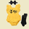 Baby girl wearing a bumble bee romper for her 1st birthday cake smash photoshoot