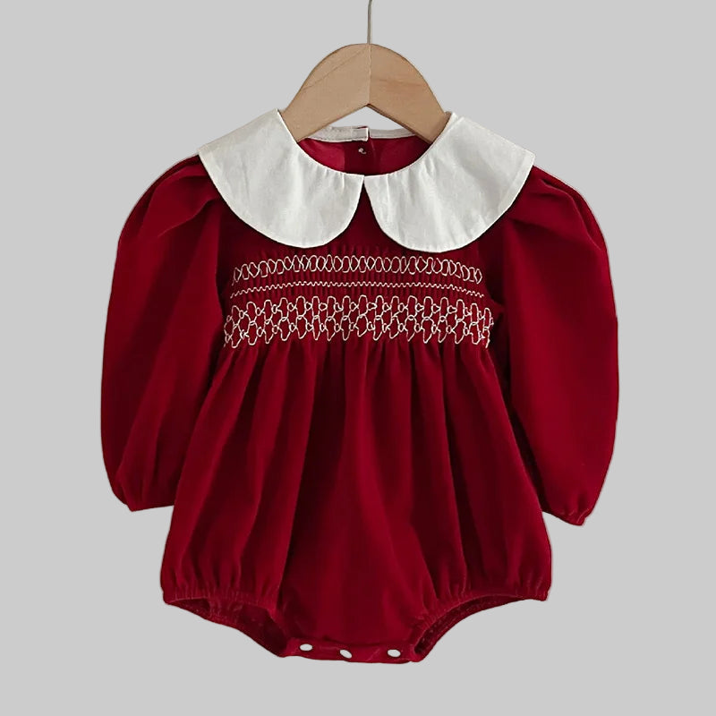 Red baby romper with white collar on a hanger against a plain background